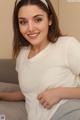 A woman in a white shirt sitting on a couch.