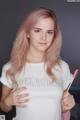 A young woman with pink hair holding a lollipop.