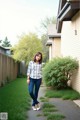 A woman walking down a sidewalk in front of a house.