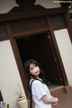 A woman standing in front of a building wearing a white shirt.