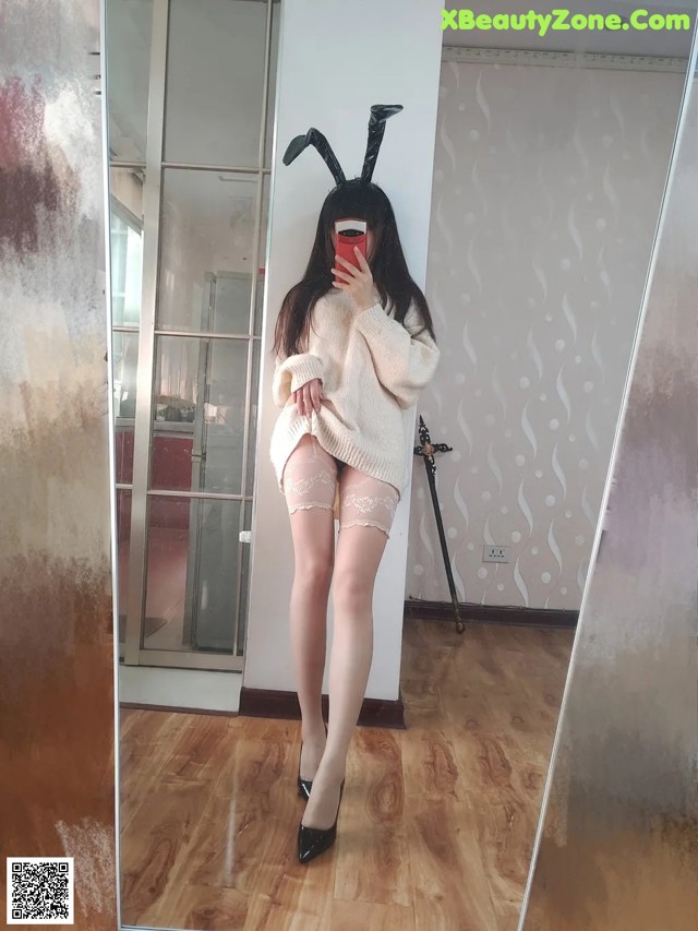 A woman in a bunny costume taking a selfie in a mirror.