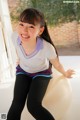 A young girl sitting on an exercise ball smiling.