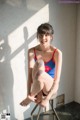 A woman in a red and blue bathing suit sitting on a stool.