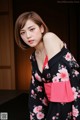 A woman in a black and pink kimono posing for a picture.