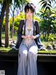 A woman in a kimono sitting on a bench in a park.