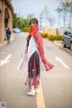 A woman in a red and white dress is walking down the street.